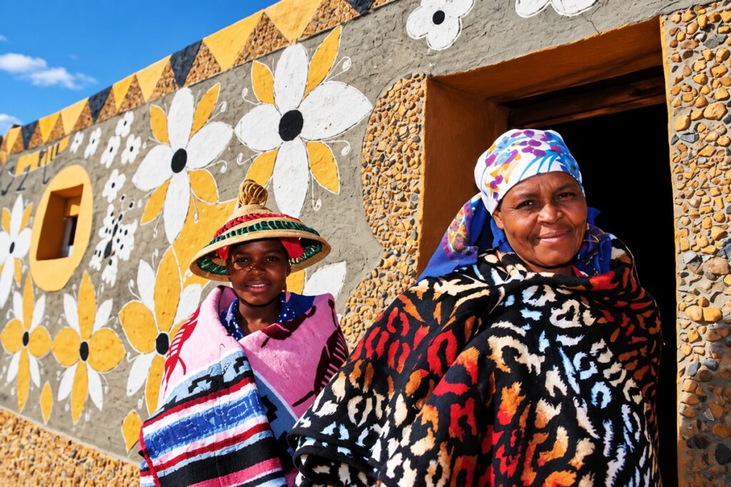 femmes basotho devant une maison peinte litema