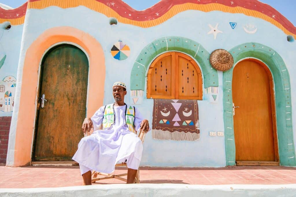 homme nubien devant sa maison colorée