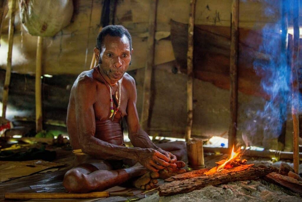 homme korowai près du feu