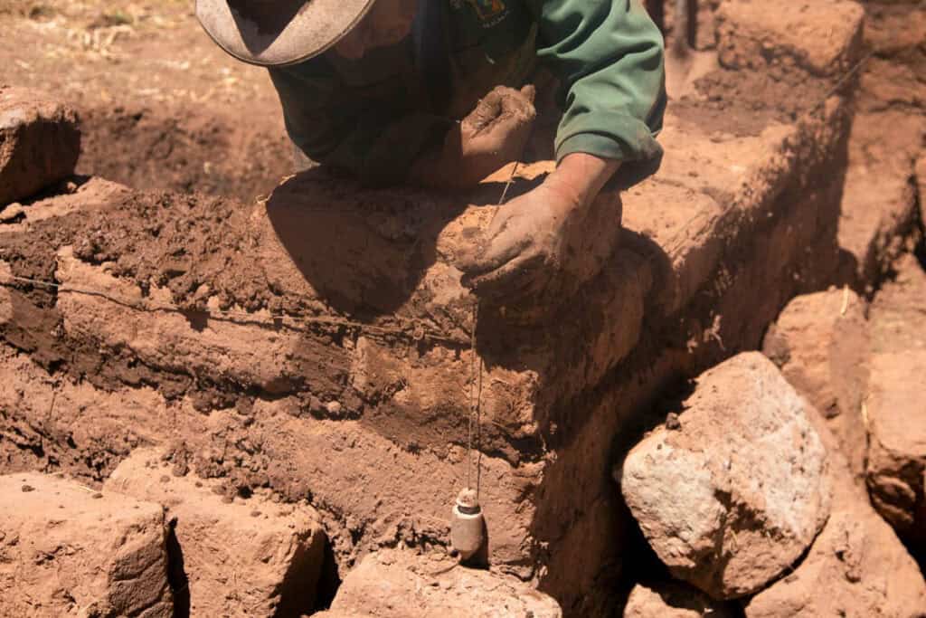 homme construit mur de maison en briques d'adobe