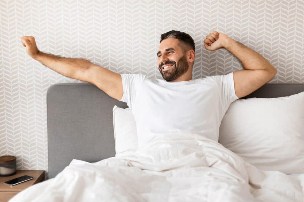 homme se réveillant heureux sur son matelas de qualité