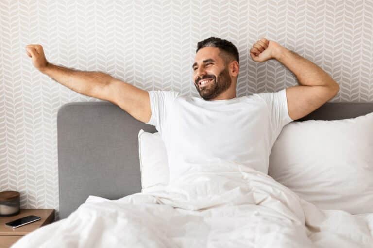 homme se réveillant heureux sur son matelas de qualité