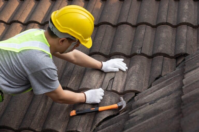 homme qui répare une toiture en tuiles