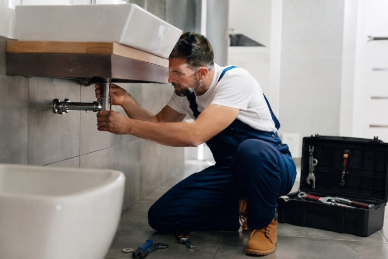 plombier qui débouche une canalisation sous un évier