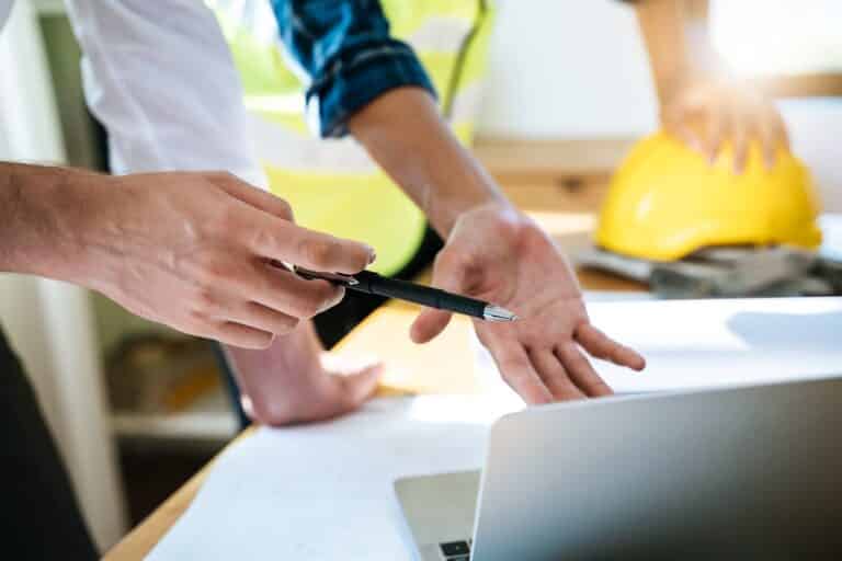 le promoteur explique au client le plan de construction présenté sur la table.