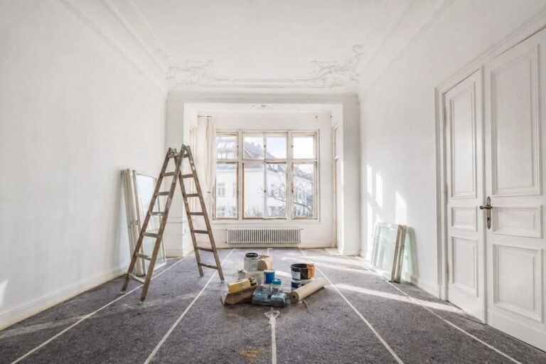 pièce en travaux avec des pots de peinture et un escabeau au centre