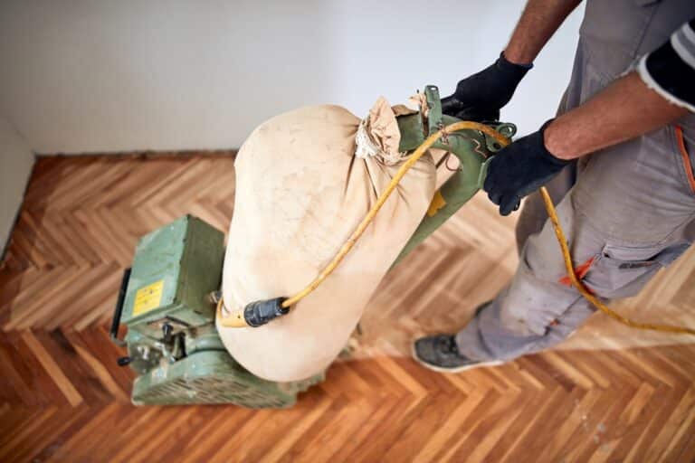 homme ponçant un parquet avec une machine
