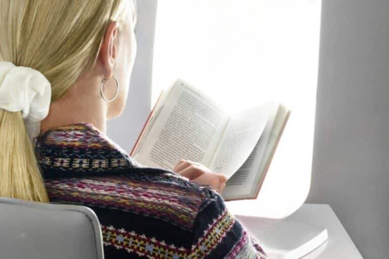 femme lisant un livre sous une lampe de luminothérapie