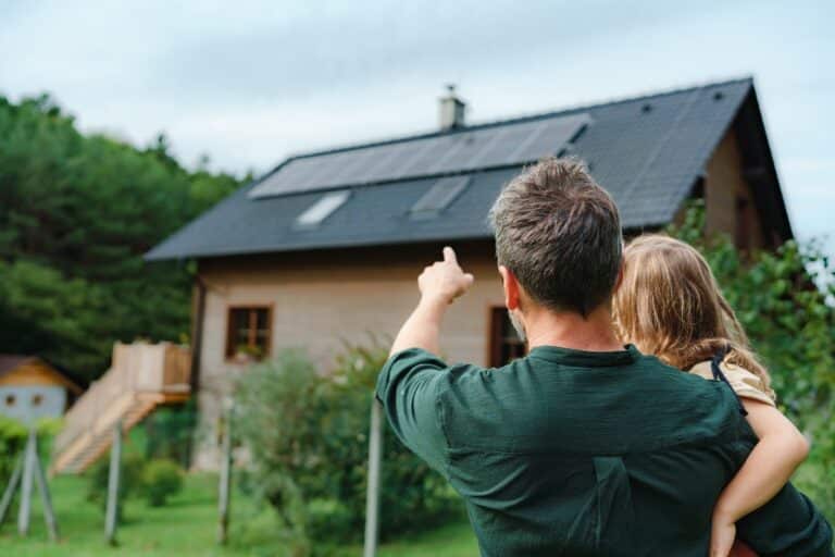 couple regardant leur maison avec panneaus solaires sur le toit