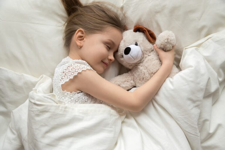 gros plan sur un enfant qui dort dans des draps blancs