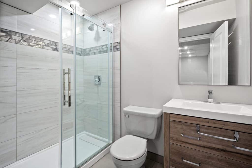 salle de bain avec toilettes et porte de douche moderne en verre