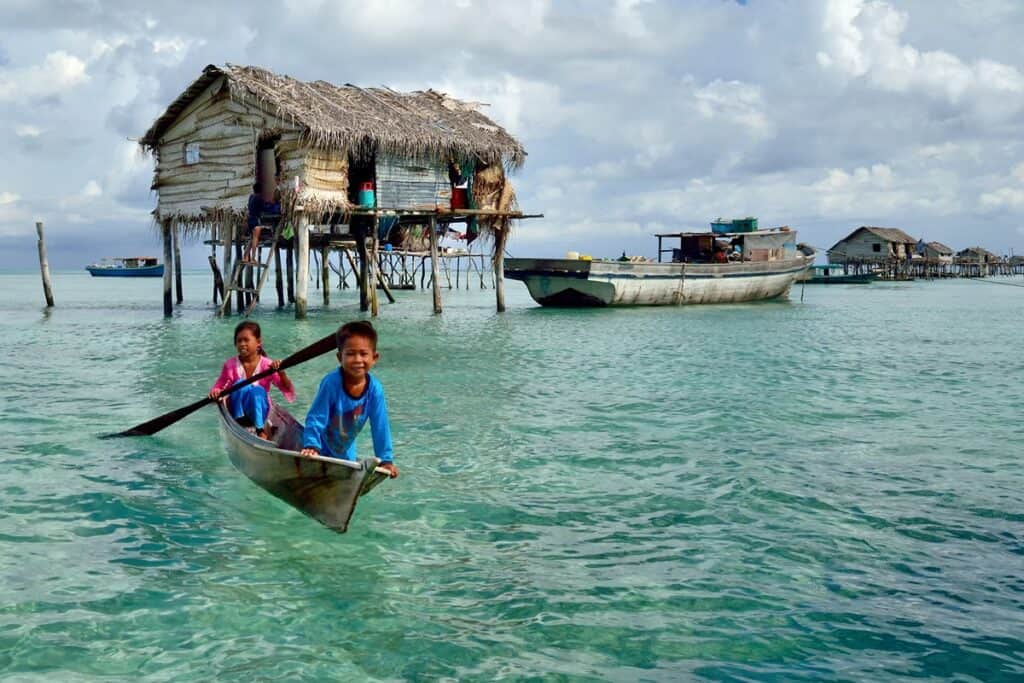 enfants badjao devant une maison sur pilotis