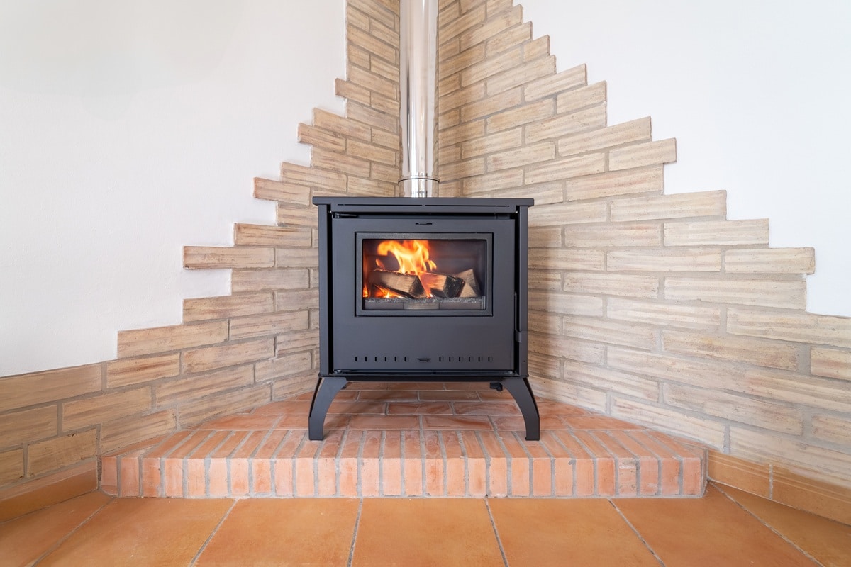 beau poêle à bois installé dans un angle de pièce