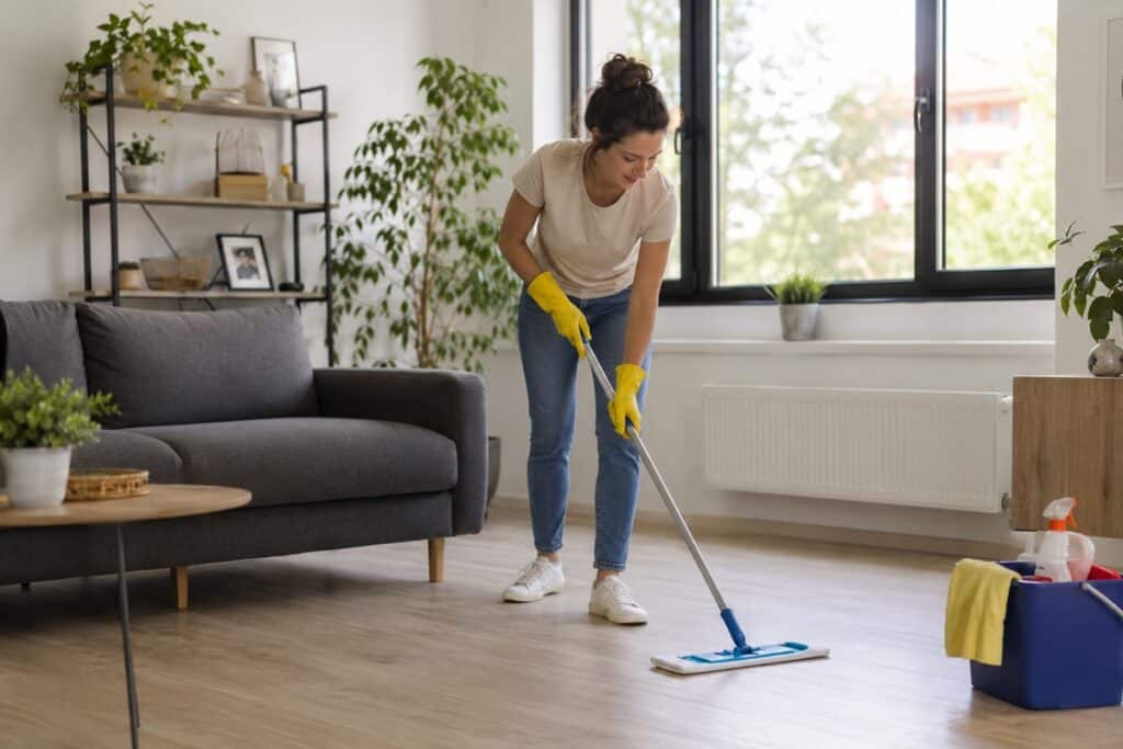 femme qui lave le parquet dans un salon lumineux