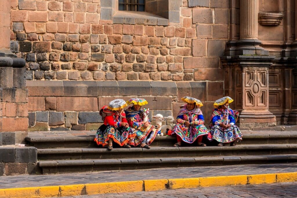 Femmes quechua en costume traditionnel devant un mur de Qorikancha