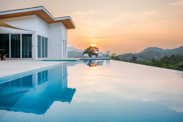 Villa moderne de luxe avec piscine à débordement surplombant les collines tropicales au coucher du soleil sur Koh Samui